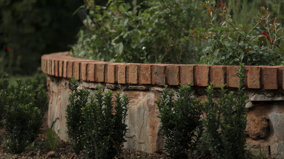 Circular stone raised bed with brick coping and young box hedging in the finished formal garden