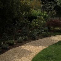 Gravel path curving past a deep mixed border with a Japanese maple and metal arch
