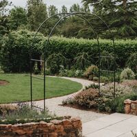 Metal arch over the gravel path, with the circular lawn and stone-edged bed behind