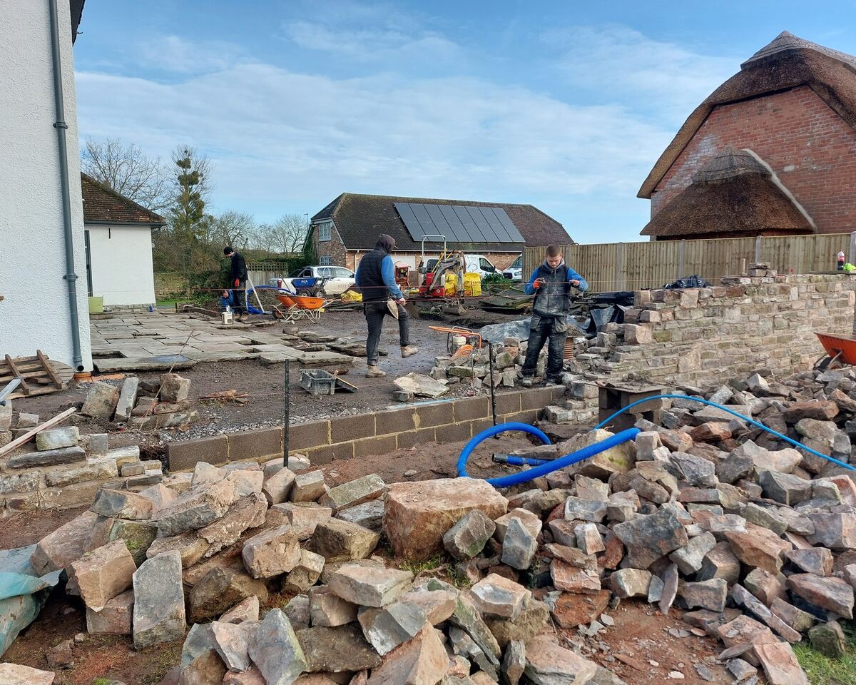Workers clearing rubble and debris at a construction site with buildings in the background.