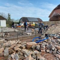 Workers clearing rubble and debris at a construction site with buildings in the background.