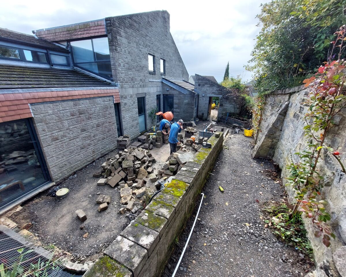 Construction site with workers and stone materials beside a modern building.