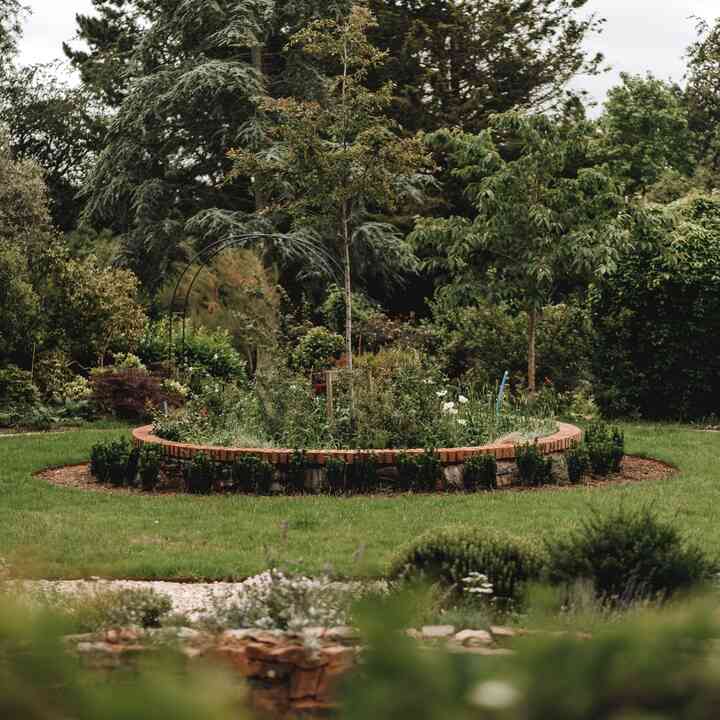 Brick-edged circular planting bed set into the lawn at the centre of the formal garden