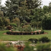 Brick-edged circular planting bed set into the lawn at the centre of the formal garden