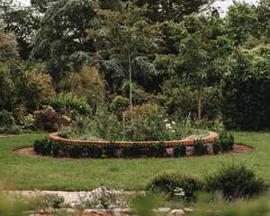 Brick-edged circular planting bed set into the lawn at the centre of the formal garden