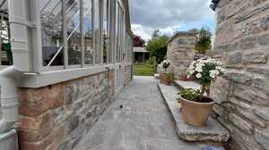 Reclaimed stone wall and paved terrace leading to the greenhouse, part of a Somerset garden landscaping project