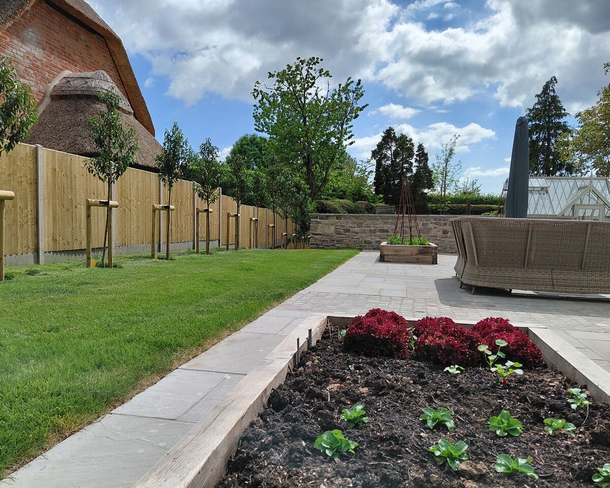 Garden with greenery, flower beds, and a landscaped area under a partly cloudy sky.