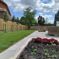 Garden with greenery, flower beds, and a landscaped area under a partly cloudy sky.