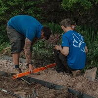 Two Sibley Landscapes team members levelling steel edging for one of the circular beds