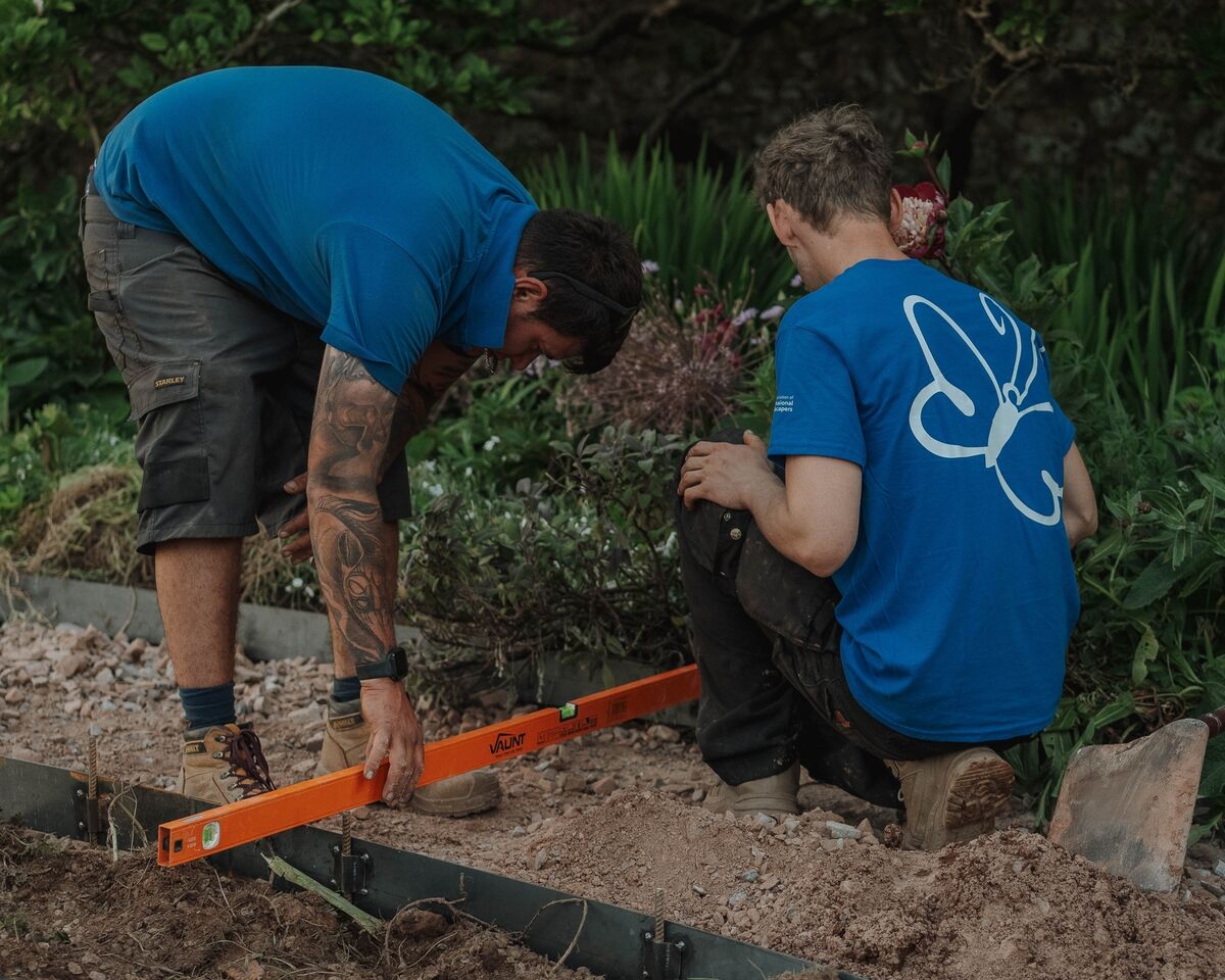 Two Sibley Landscapes team members levelling steel edging for one of the circular beds