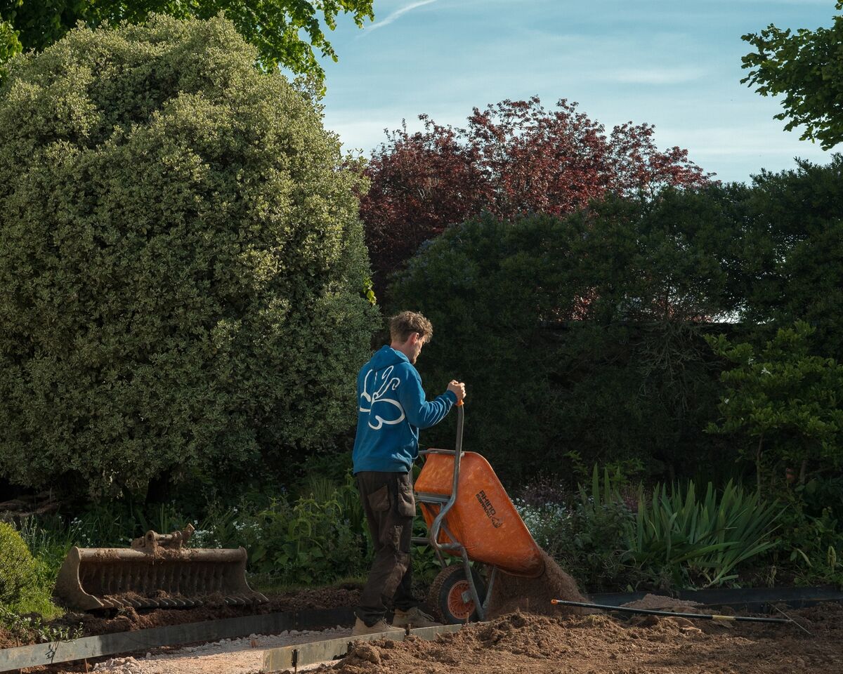 Sibley Landscapes team member barrowing material across the excavated garden during the build