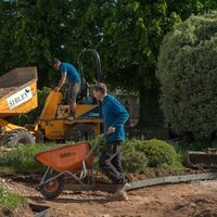 Sibley Landscapes dumper unloading while a team member barrows material to the new beds