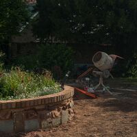 Cement mixer beside the part-built brick and stone circular retaining wall