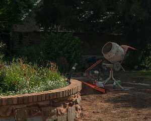 Cement mixer beside the part-built brick and stone circular retaining wall