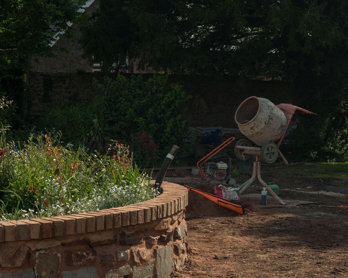 Cement mixer beside the part-built brick and stone circular retaining wall