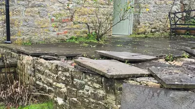 Weathered stone wall and overgrown corner before garden landscaping