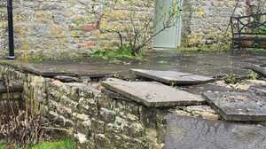 Weathered stone wall and overgrown corner before garden landscaping