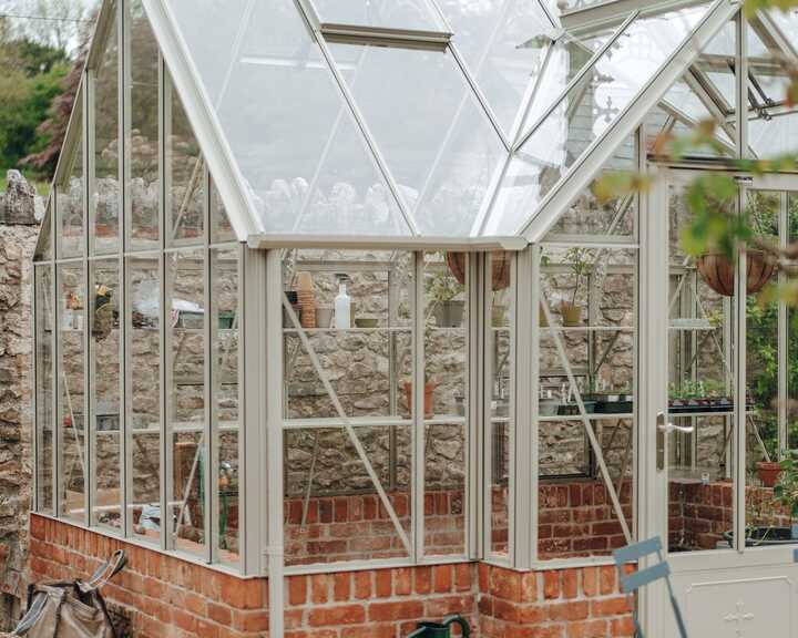 Heritage-style greenhouse with decorative roof cresting on a red brick plinth