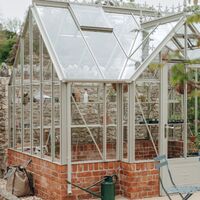 Heritage-style greenhouse with decorative roof cresting on a red brick plinth