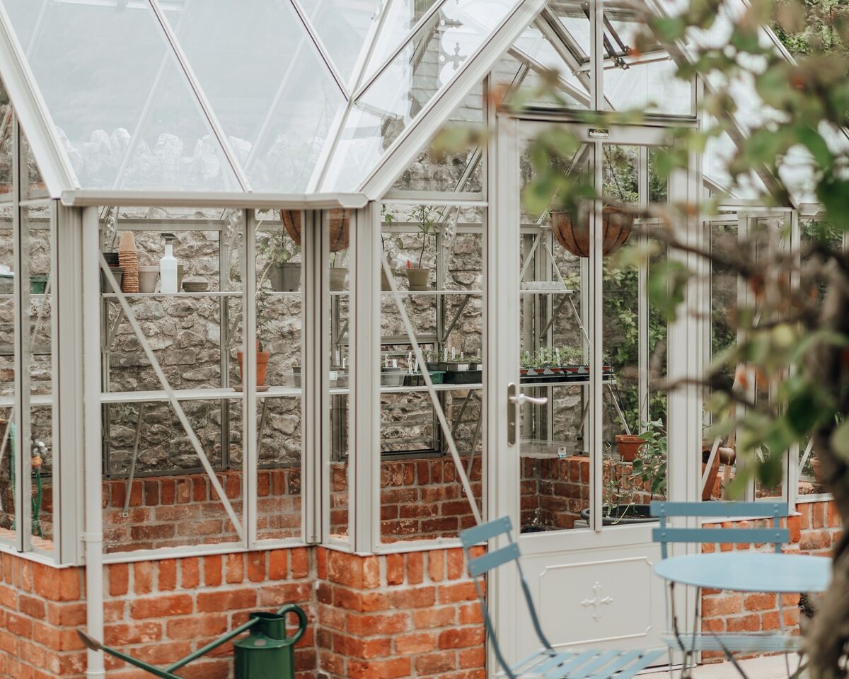 Glazed greenhouse roof and ridge finials seen from the walled garden
