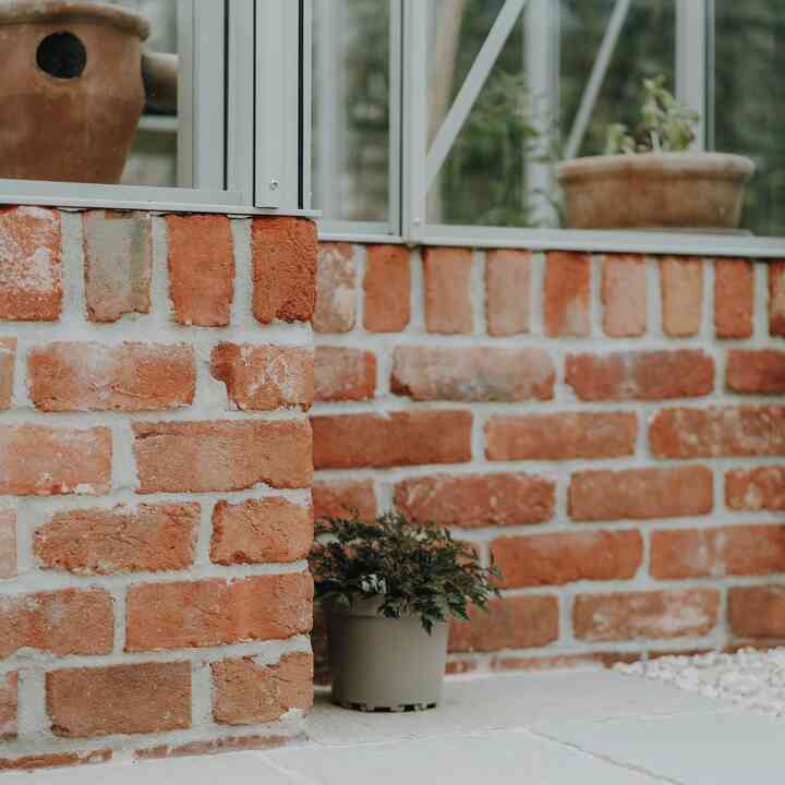 Terracotta pots inside the greenhouse above its red brick base