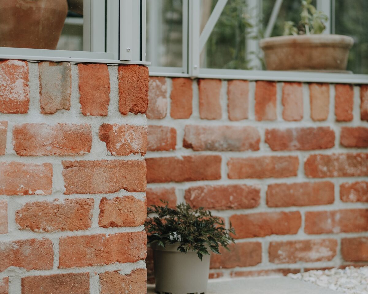 Terracotta pots inside the greenhouse above its red brick base