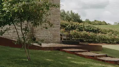 Curved corten steel retaining wall and new steps on a landscaped sloping garden