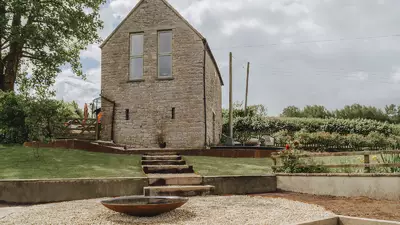 Terraced sloping garden with steps and gravel after landscaping, stone outbuilding behind, Weare, near Axbridge