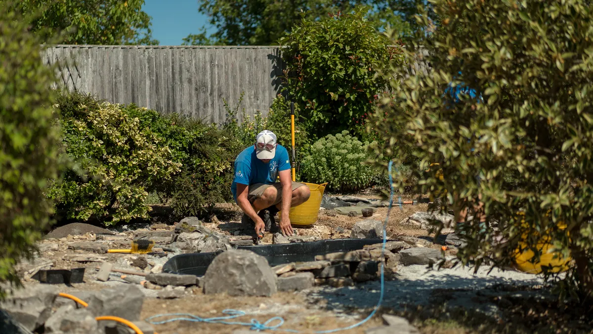 Sibley Landscapes team member laying stone paving in a garden under construction