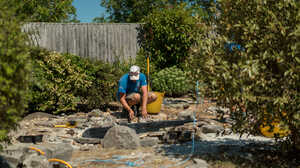 Sibley Landscapes team member laying stone paving in a garden under construction