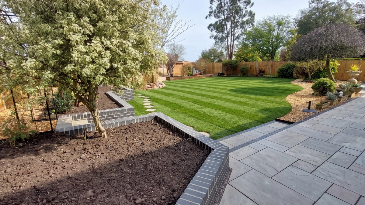 Professionally landscaped family garden with raised planting beds, bark mulch borders, and a striped lawn in Somerset