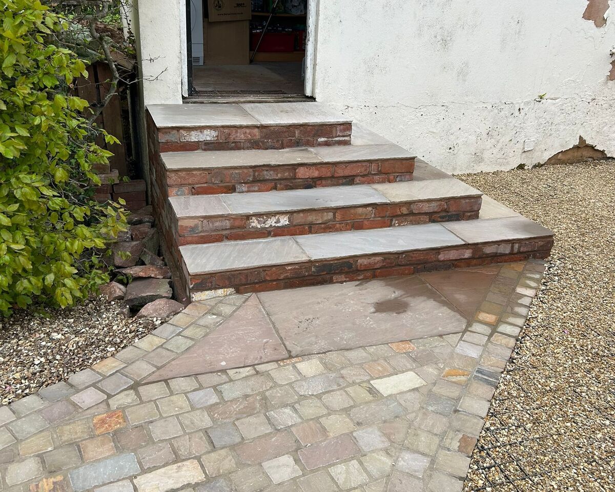 Stone steps lead up to a door, with a paved pathway beside them.