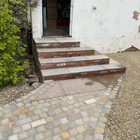 Stone steps lead up to a door, with a paved pathway beside them.