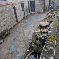 A garden area with stone walls, a pond, and a pathway decorated with blue flowers.