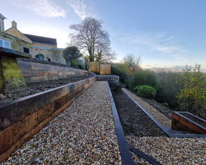 Landscape view of a terraced garden with gravel paths and a distant house.
