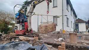 Excavator lifting reclaimed stone during groundworks for a garden transformation in Somerset