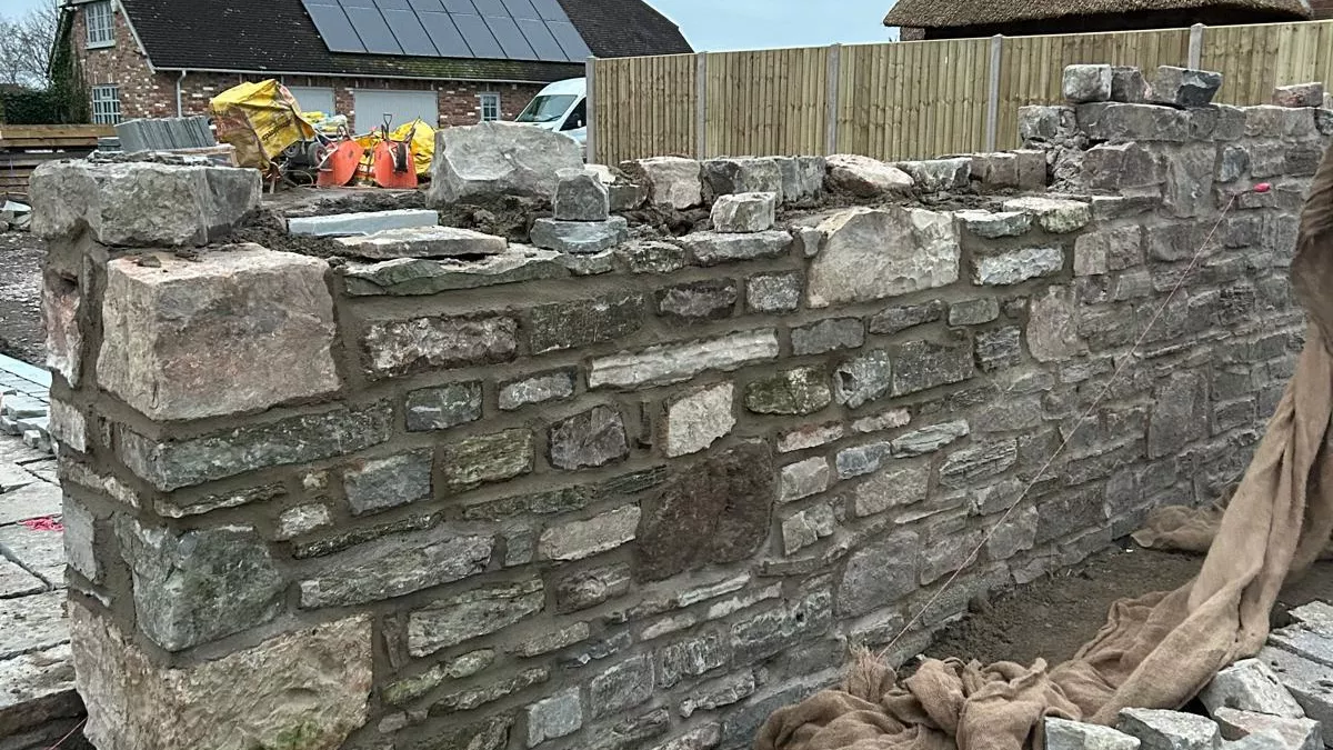 Close-up of reclaimed Lias stone being used to rebuild a garden wall