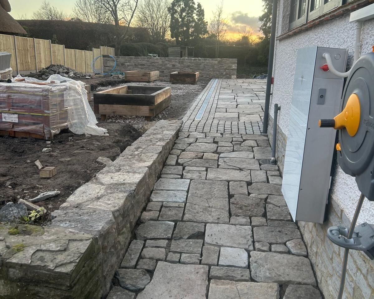 Stone pathway leading to a house, under a colorful sunset sky.