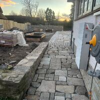 Stone pathway leading to a house, under a colorful sunset sky.