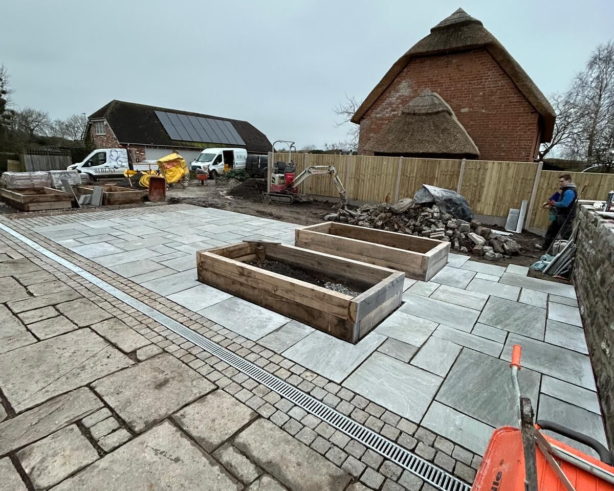 Construction site with paved area, wooden frames, and construction vehicles.
