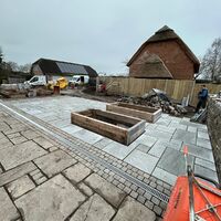 Construction site with paved area, wooden frames, and construction vehicles.