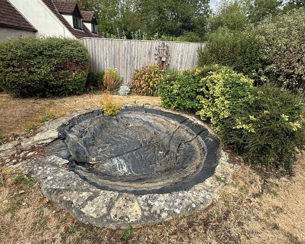 Old circular pond with an empty liner and dry lawn before the new pond was built