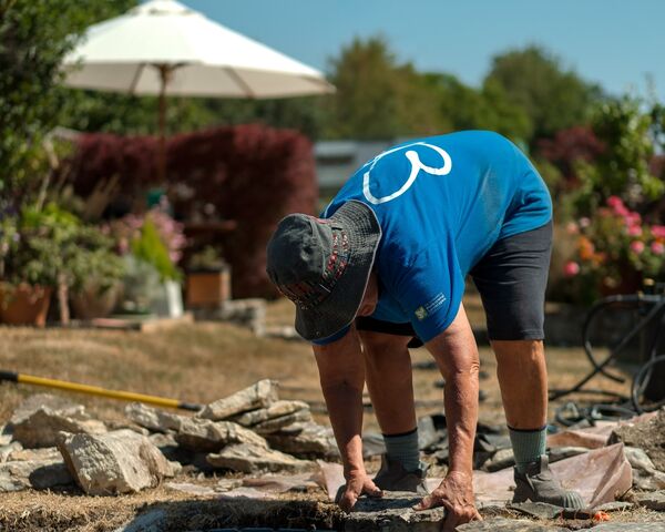 Sibley Landscapes team member bending to lay stone edging around the new pond