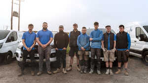 Garden with raised planter beds, green grass, and trees under a cloudy sky.